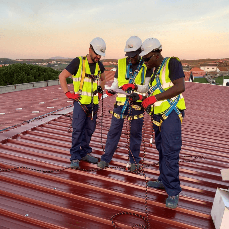 Workers with helmets and vests installing solar panels on a rooftop